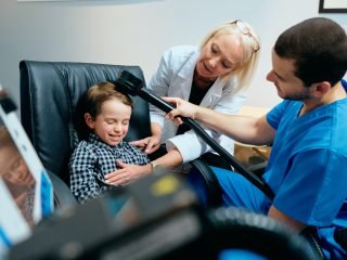 Paediatrician Doctor Doing Brain Treatment To Autistic Child In Clinic